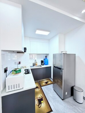 Una cocina moderna con armarios blancos, un refrigerador de acero inoxidable y una cafetera.