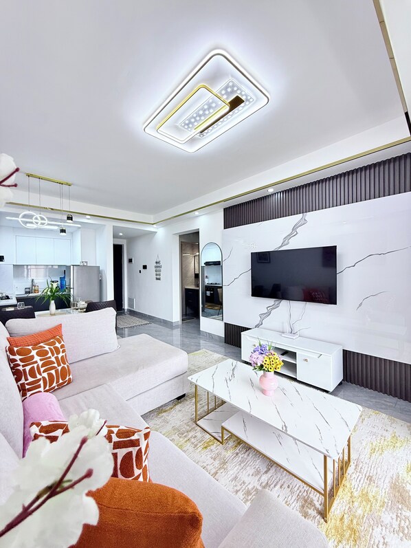 Una sala de estar moderna con un sofá, una mesa de centro y un televisor montado en una pared de mármol.