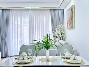 A dining area with a table set for four, featuring white and gold dinnerware, clear glassware, and a central plant. - Stylish Kilimani 2BR with Pool, Wi-Fi and Free Parking near Yaya Centre (Nairobi)