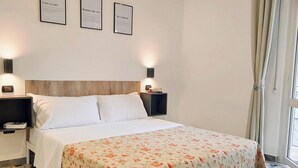 Ein Hotelzimmer mit einem Bett, zwei Nachttischen und drei gerahmten Zitaten an der Wand.
