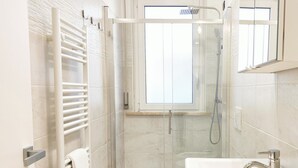 Ein modernes Badezimmer mit einer gläsernen Dusche, einem weißen Waschbecken und einem Handtuchhalter.