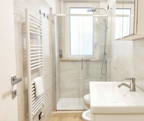A modern bathroom with a glass-enclosed shower, a white sink, and a towel rack. - Casa Vacanze Saint Tropez Pineto (Pineto)
