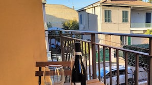 Ein Balkon mit Holztisch, einer Weinflasche und einem Weinglas.