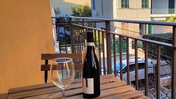A balcony with a wooden table, a wine bottle, and a wine glass.