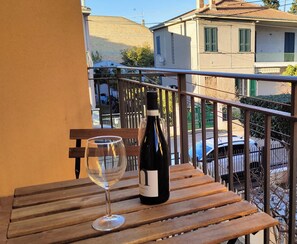 A balcony with a wooden table, a wine bottle, and a wine glass. - Casa Vacanze Saint Tropez Pineto (Pineto)