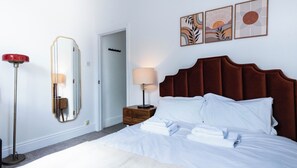 A hotel room with a bed, a nightstand, a lamp, a mirror, and artwork on the wall. - The Stanley Arms Hotel by Guestz (Seascale)