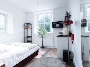 A bedroom with a bed, a radiator, a window, a plant, and a television. - The Stanley Arms Hotel by Guestz (Seascale)