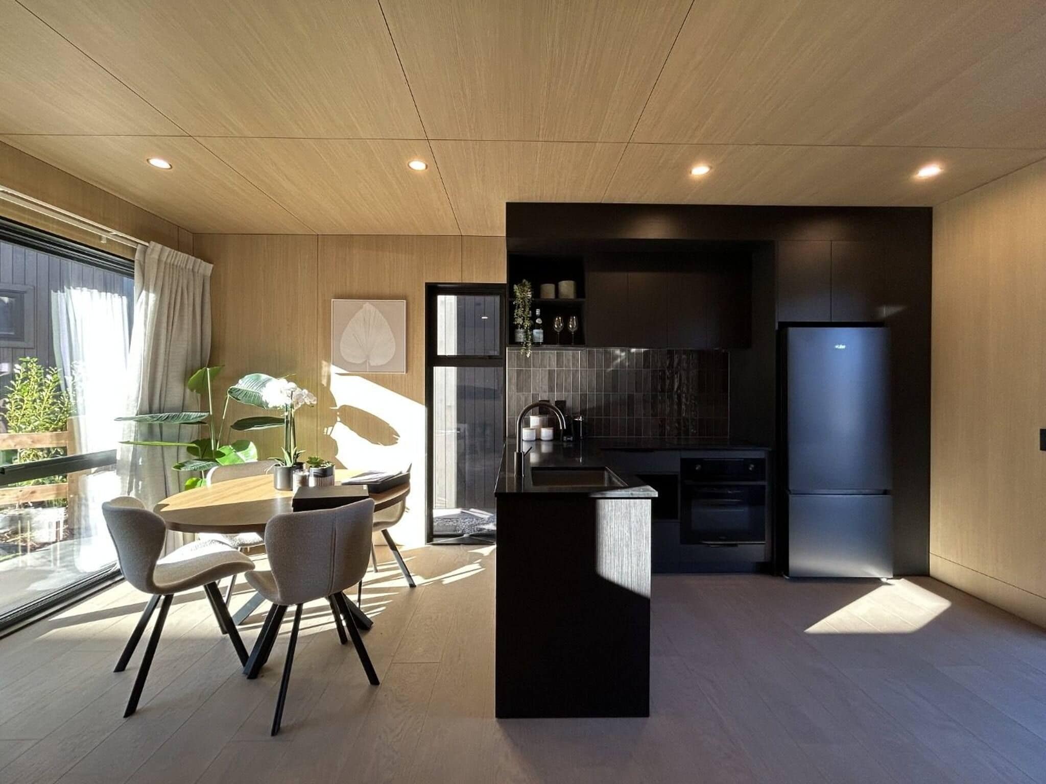 A modern kitchen with a black island, a built-in oven, and a refrigerator.