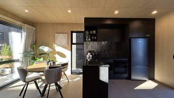 A modern kitchen with a black island, a built-in oven, and a refrigerator.