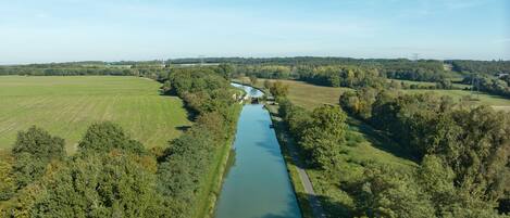 Eine Luftaufnahme eines Flusses mit einer Brücke, umgeben von grünen Feldern und Bäumen.