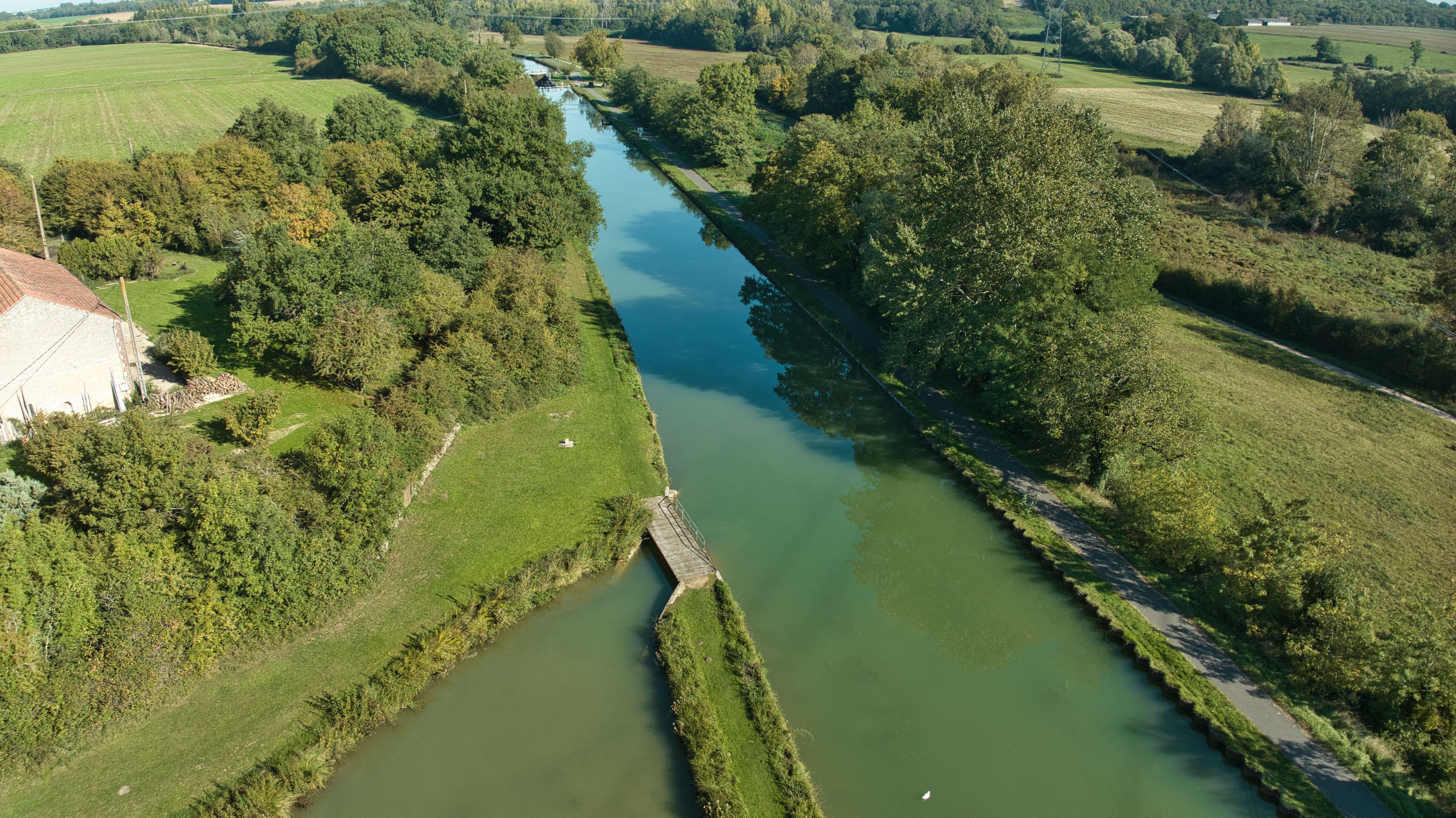 A river with a narrow bridge and surrounding greenery.