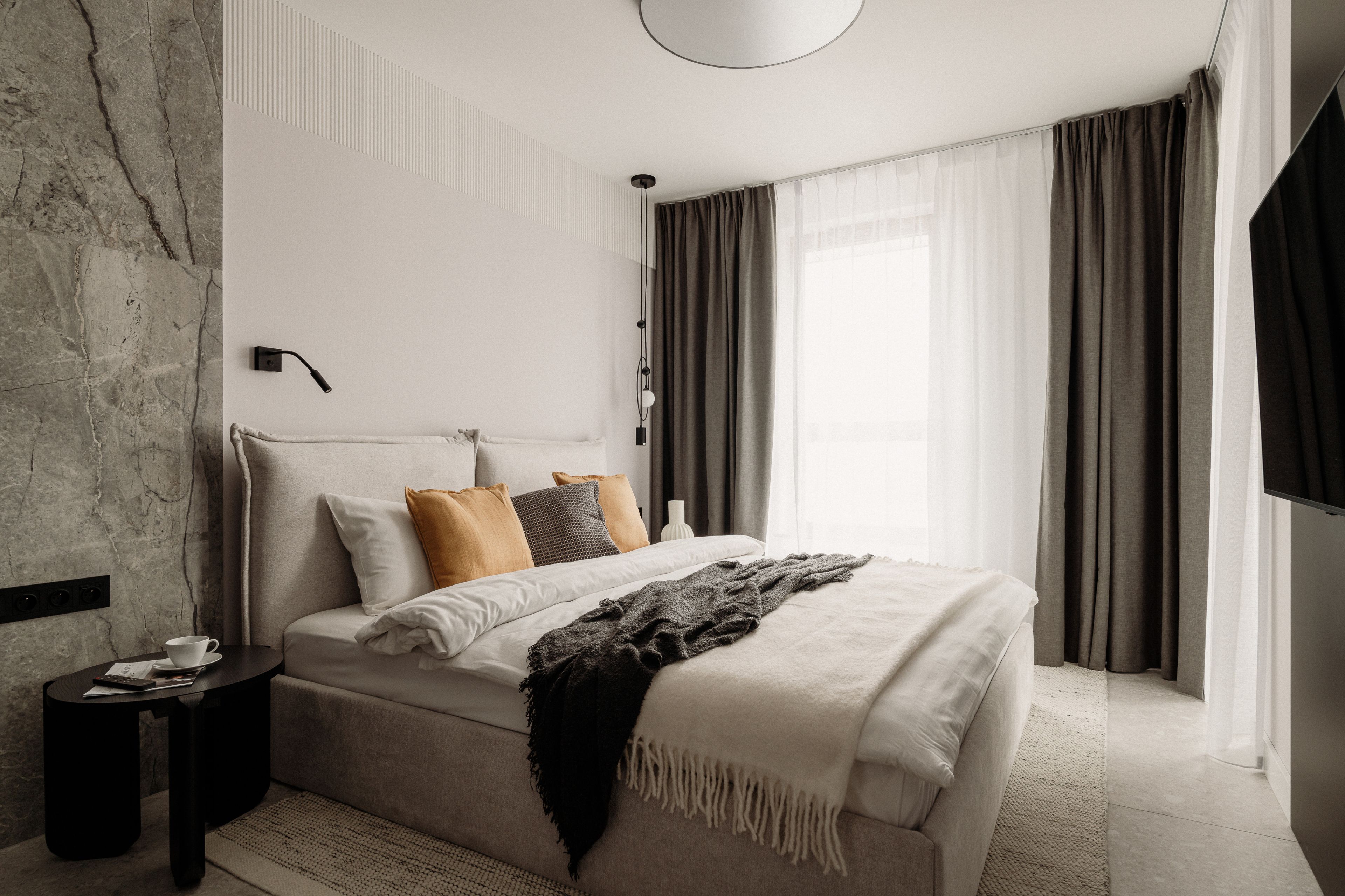Ein modernes Schlafzimmer mit einem großen Bett, einem Nachttisch und einer Wandleuchte.