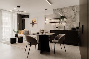 A modern living room with a round dining table, two chairs, a sofa, and a coffee table.