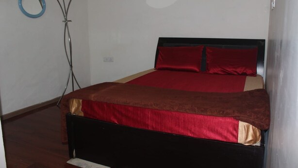 Un dormitorio con una cama, una colcha marrón y roja, y un objeto circular azul en la pared.