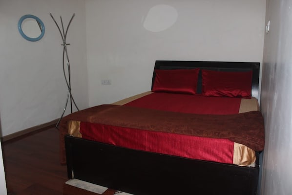 A bedroom with a bed, a red and brown bedspread, and a blue circular object on the wall. - VISA HOMESTAY
Private Cottage @ Your Budget
family-friendly and pet-friendly (Kodaikanal)
