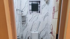 Un baño pequeño con inodoro, lavamanos y zona de ducha.