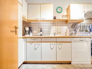 A kitchen with white cabinets, a coffee maker, a wine bottle, and a dishwasher. - 7a/t5 in the Holiday Apartment Park "freesenbruch" (Zingst)