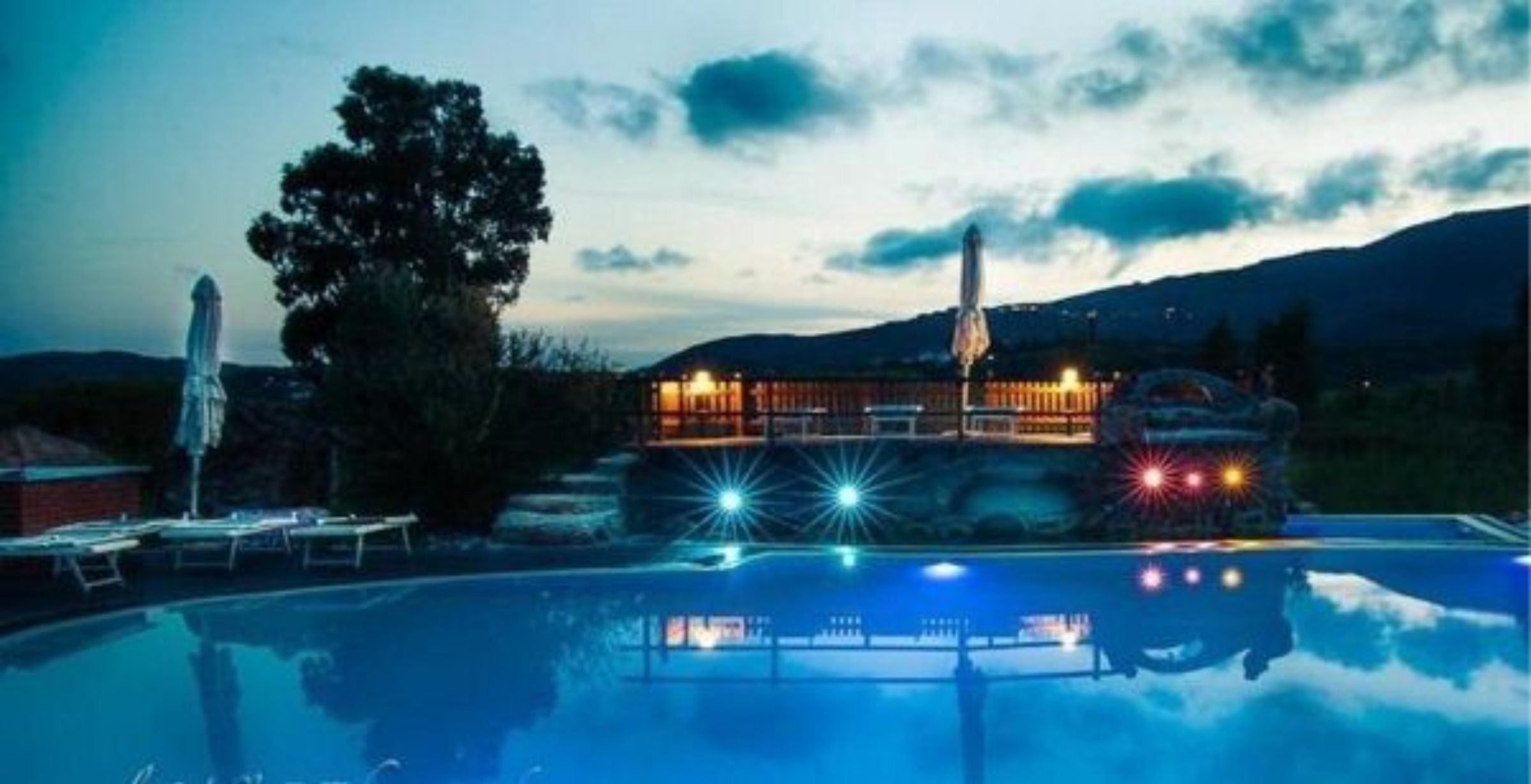 Una piscina con vistas a un edificio y montañas al fondo.