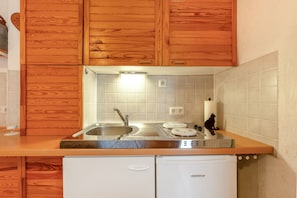 A kitchen with wooden cabinets, a stainless steel sink, a white dishwasher, and a tiled backsplash.
