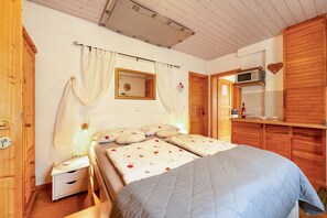 A bedroom with a bed, bedside tables, a wardrobe, a mirror, and a wall-mounted microwave. - Studio Apartment 'Röschen' with Shared Garden and Wi-Fi (Kirn)