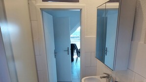 A modern bathroom with a bathtub, a sink, and a mirror. There is a door leading to another room. - Beautiful 1-bedroom apartment in charming Winden perfect for relaxing (Winden)