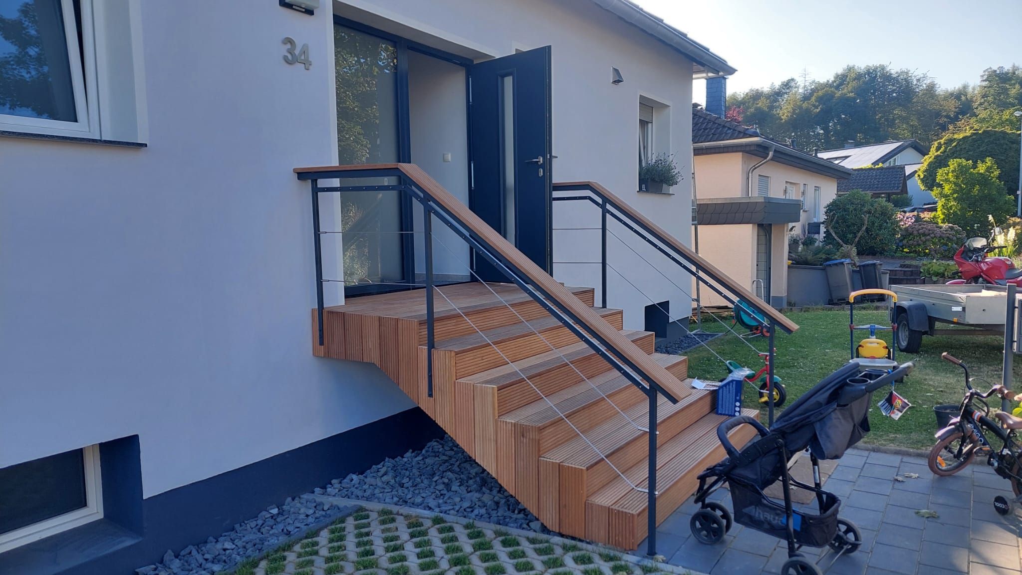Ein modernes Haus mit einer Holztreppe, die zu einem Balkon führt.
