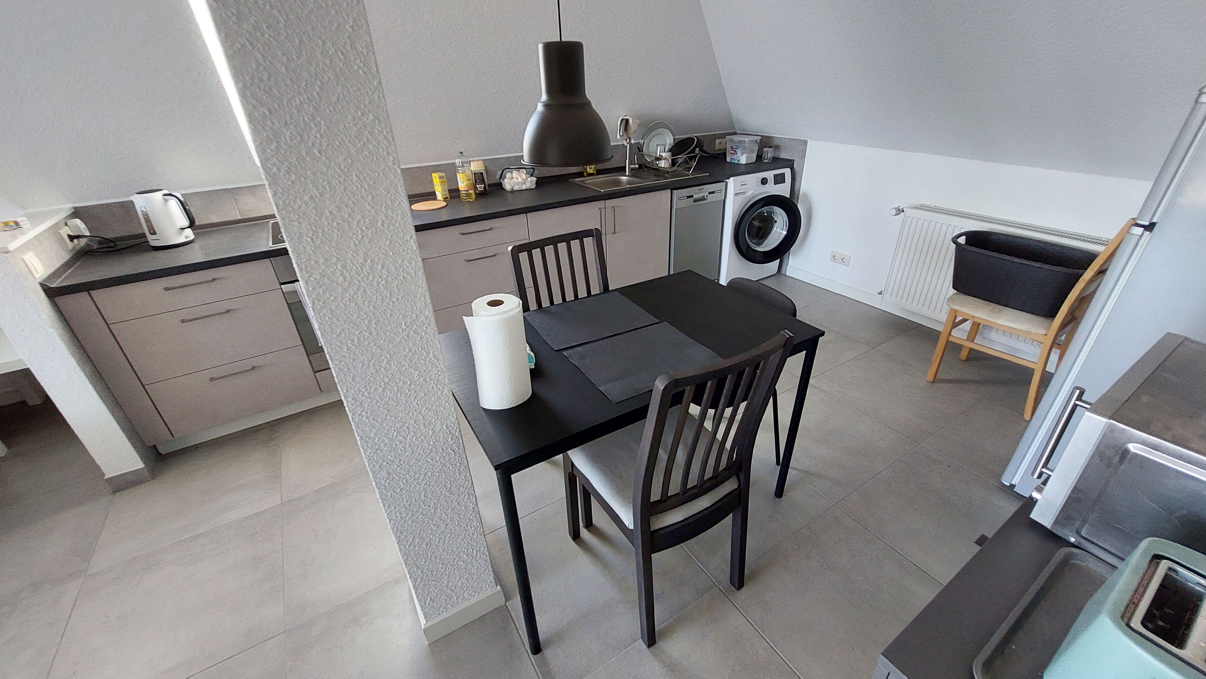 Une cuisine compacte comprenant un lave-linge, une table à manger avec des chaises et un petit coin salon.