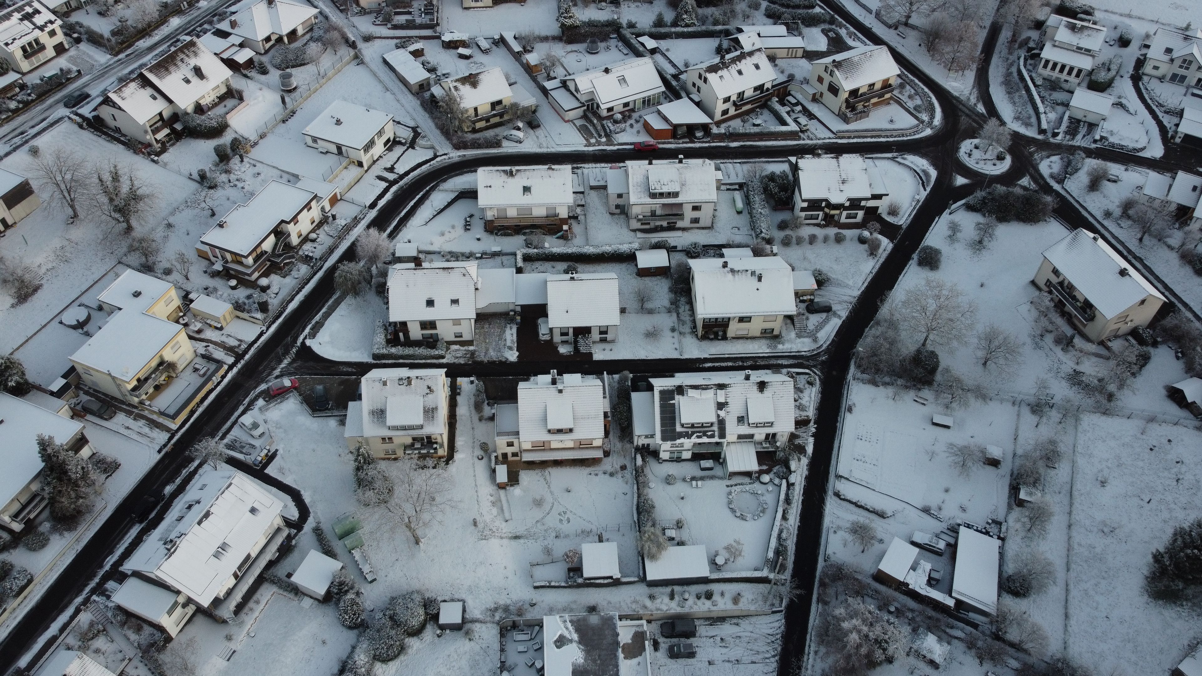 Ett flygbildsbild av ett bostadsområde med flera hus, vägar och en liten vattenväg.