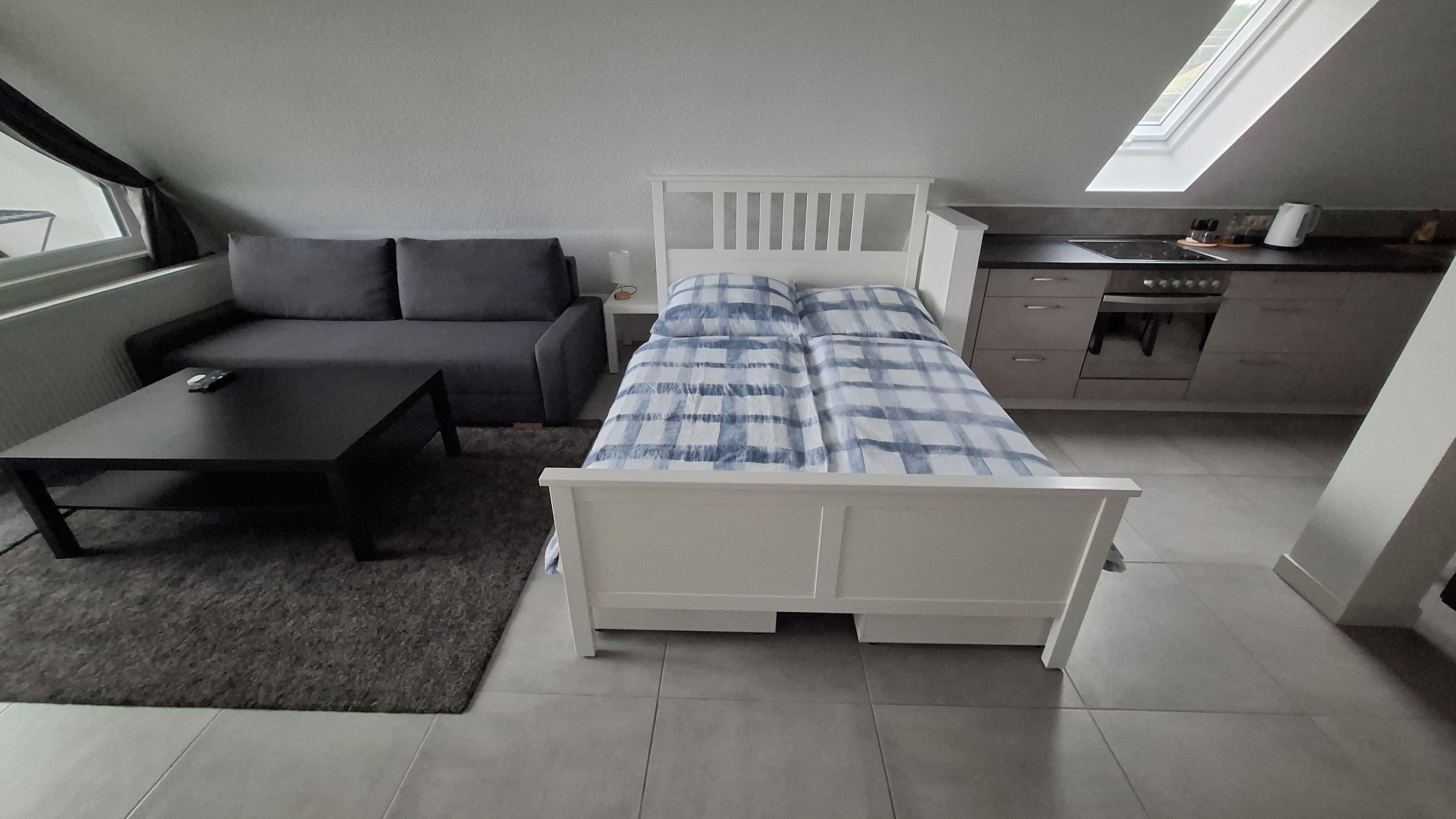 Ein kleines Zimmer mit Bett, Esstisch, Sofa und Küchenzeile.