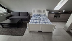 Ein kleines Zimmer mit Bett, Esstisch, Sofa und Küchenzeile.