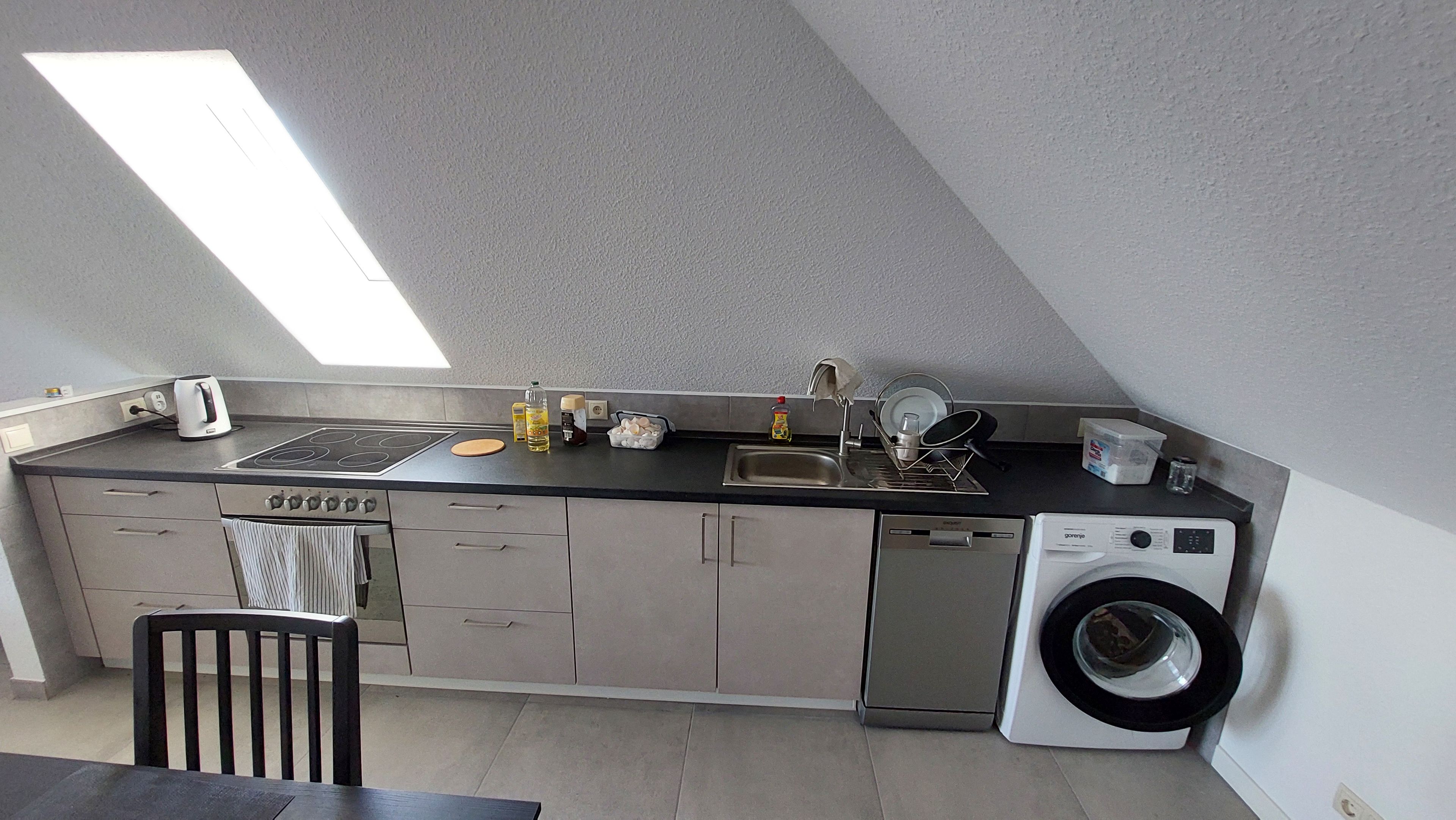 Eine kleine Küche mit einer eingebauten Waschmaschine, einem Toaster und einem Spülbecken.