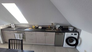 Una cocina compacta con lavadora integrada, tostadora y lavabo.