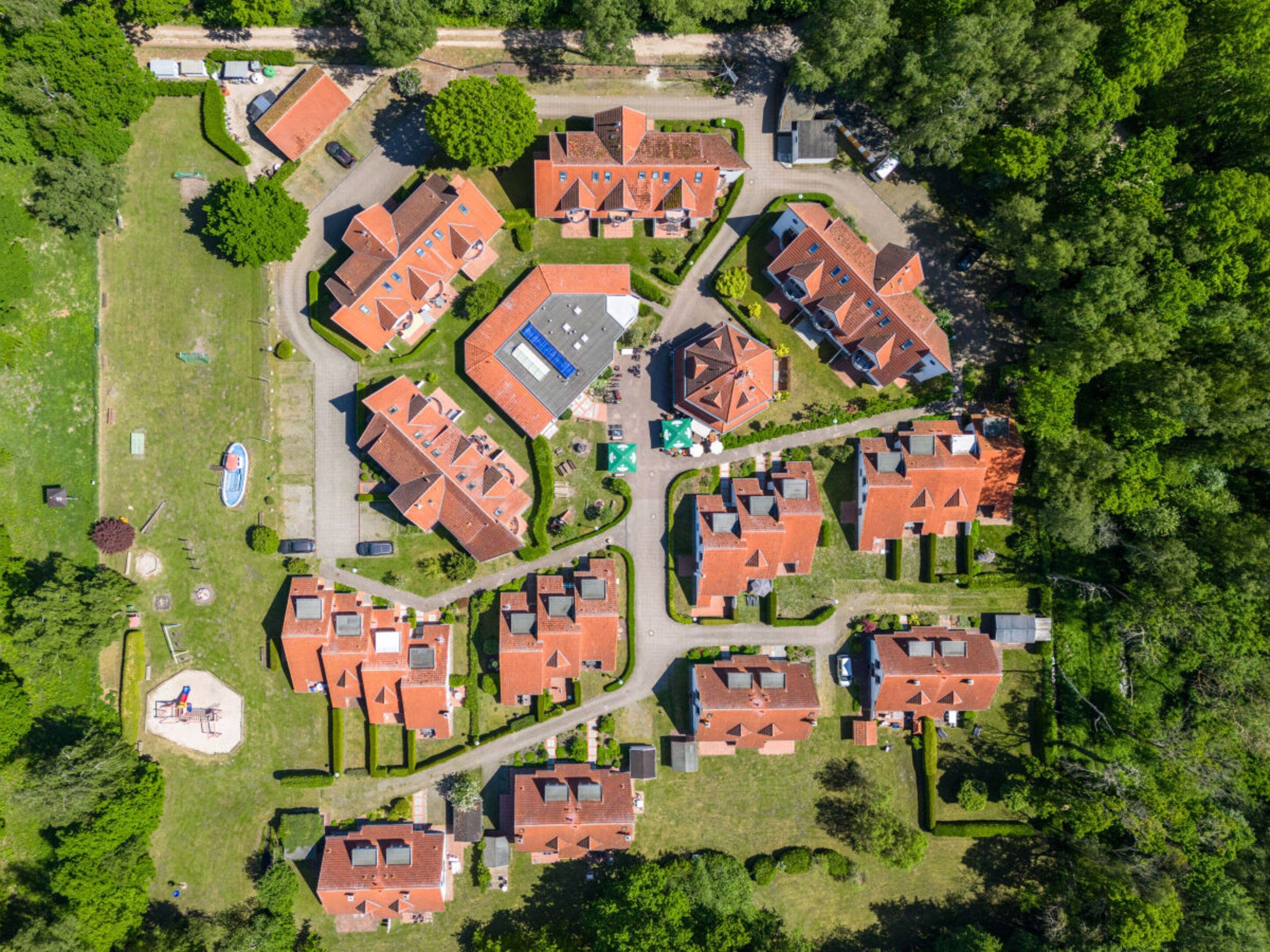 Eine Luftaufnahme eines Wohngebiets mit mehreren Häusern, grünen Rasenflächen und einem Spielplatz.
