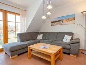 A modern living room with a sectional sofa, a wooden coffee table, and a painting on the wall. - 2.4/t1 Holiday Home Park \"freesenbruch\" (Zingst)