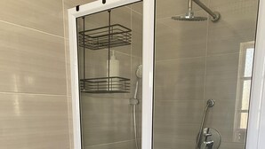 Une cabine de douche dotée d’une porte en verre, d’un pommeau de douche et d’un flexible de douche.
