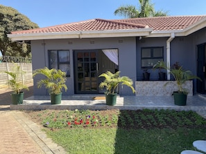 Un edificio residencial con techo de tejas, puerta principal y plantas en macetas.