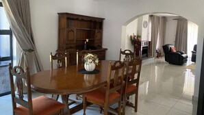 Un coin repas avec une table et des chaises en bois, un vase de fleurs et un meuble en bois.