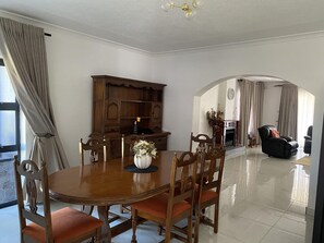 Un comedor con una mesa y sillas de madera, un florero con flores y un armario de madera.