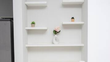 Ein helles Interieur mit einer eingebauten Regaleinheit an der Wand, einer kleinen Topfpflanze und einer Vase mit Blumen.