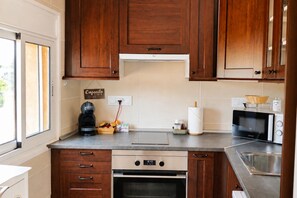 A kitchen with wooden cabinets, a coffee maker, a microwave, and a sink. - Can Costals Cerezo in Pals (Els Masos de Pals)
