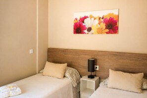 A hotel room with two beds, a nightstand with a lamp, and a floral artwork on the wall. - Can Costals Cerezo in Pals (Els Masos de Pals)