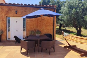 An outdoor patio with a table and chairs, a hammock, and a dog near a building with a door. - Can Costals Cerezo in Pals (Els Masos de Pals)