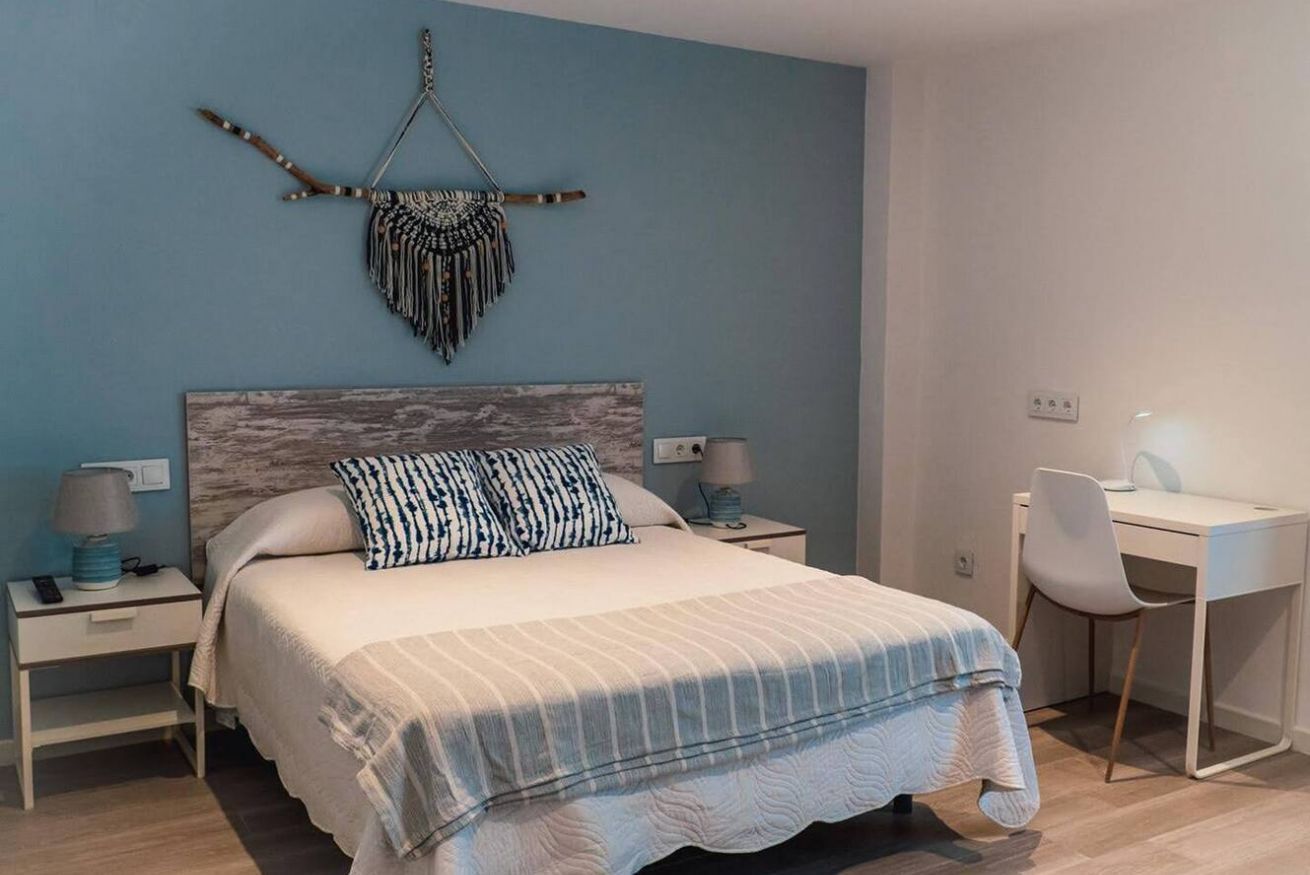 A bedroom with a bed, bedside tables, a desk, and a chair.