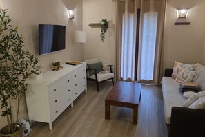 A living room with a flat-screen TV, a white cabinet, a wooden table, a sofa, and a chair. - Can Costals Olivo in Pals (Masos de Pals)