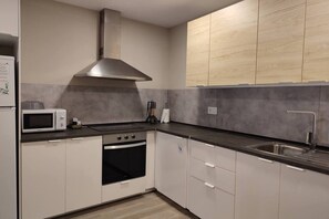 A modern kitchen with white cabinets, a stainless steel range hood, a microwave, and a sink. - Can Costals Olivo in Pals (Masos de Pals)