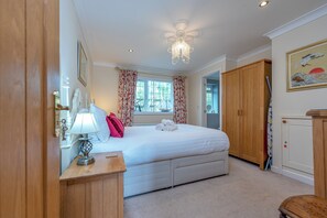 A bedroom with a bed, a bedside table with a lamp, a wardrobe, and a painting on the wall. - The Old Smithy, 2 bedroom apartment - Pass the Keys (Shropshire)