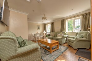 A living room with a sofa, armchairs, a coffee table, and a chandelier. - The Old Smithy, 2 bedroom apartment - Pass the Keys (Shropshire)
