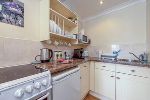 A kitchen with white cabinets, a microwave, a kettle, and a toaster. - The Old Smithy, 2 bedroom apartment - Pass the Keys (Shropshire)