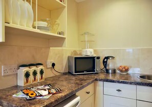 A kitchen with a microwave, a coffee maker, and a bowl of fruit on the counter. - The Old Smithy, 2 bedroom apartment - Pass the Keys (Shropshire)