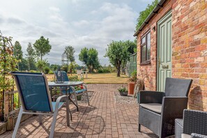Eine Terrasse mit Gartenmöbeln, einer Ziegelwand und einer grünen Tür.